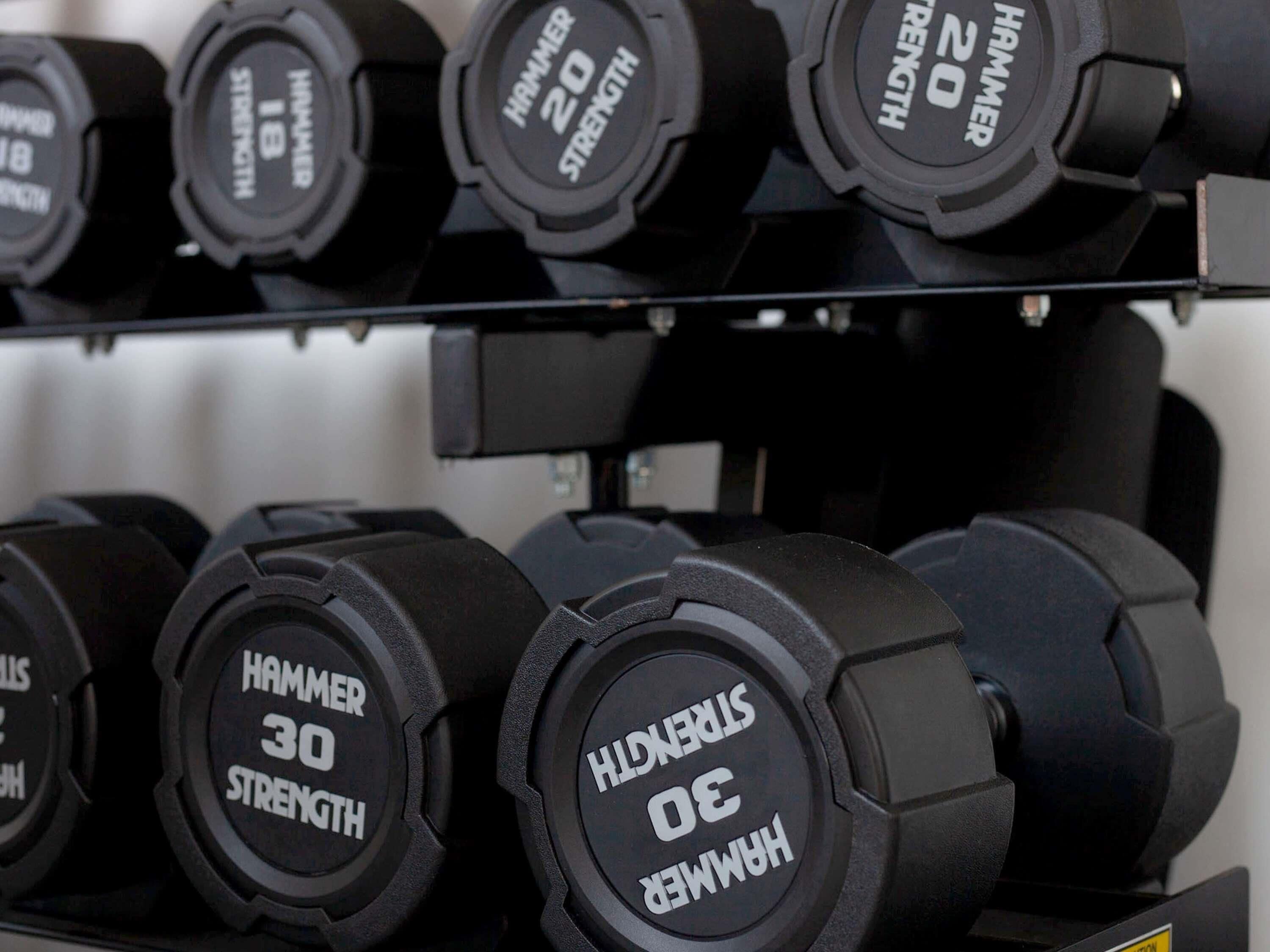 A rack of black dumbbells with labels indicating their weight in pounds.