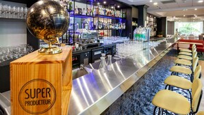 A bar area with a wooden counter labeled "SUPER PRODUCTEUR," a globe decoration, and a bar stocked with bottles and glasses. - Mercure Paris Centre Tour Eiffel (Paris)