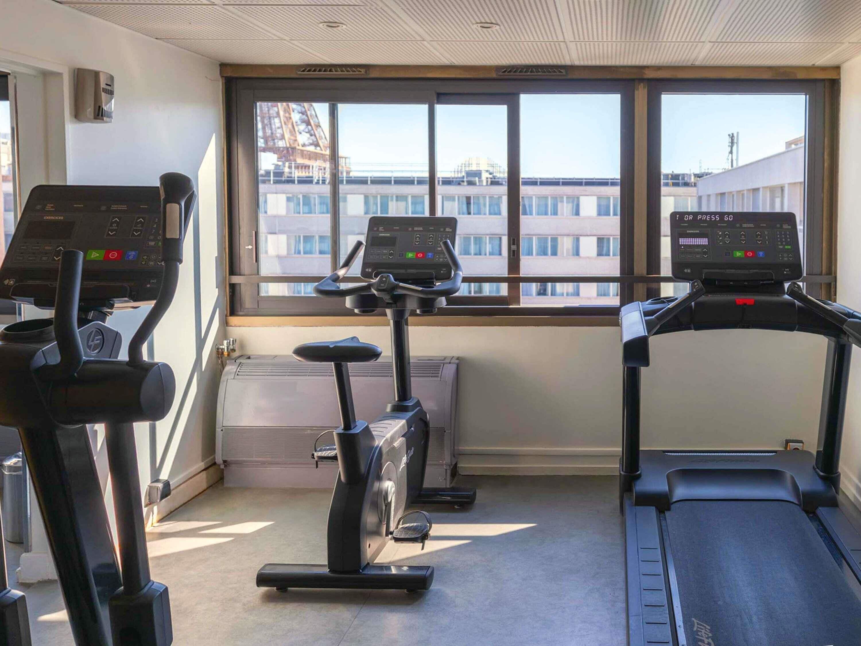 Ein Fitnessraum mit drei Laufbändern, einem Ergometer und einer wandmontierten Klimaanlage.