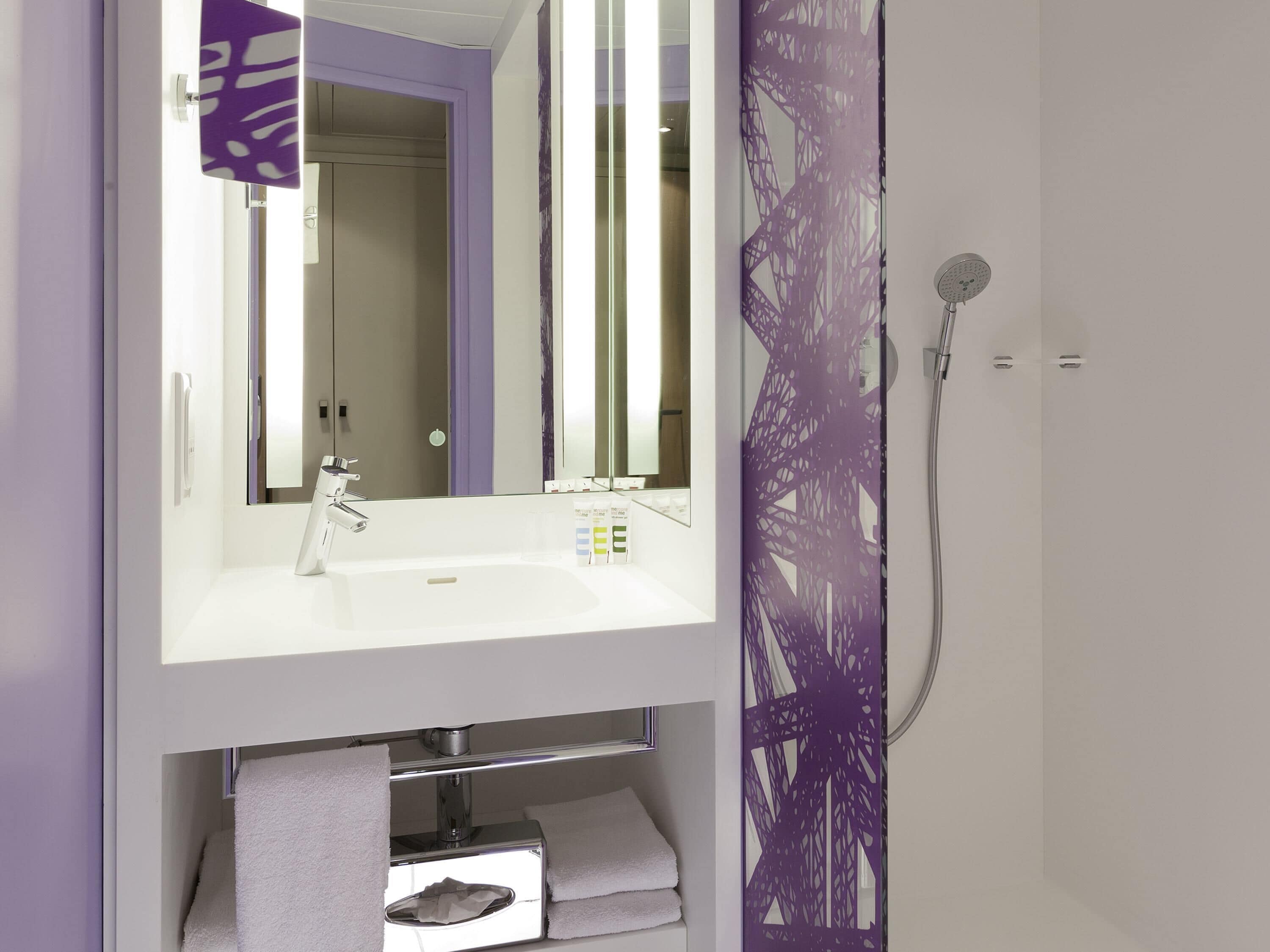 A modern bathroom with a white sink, mirror, and shower.