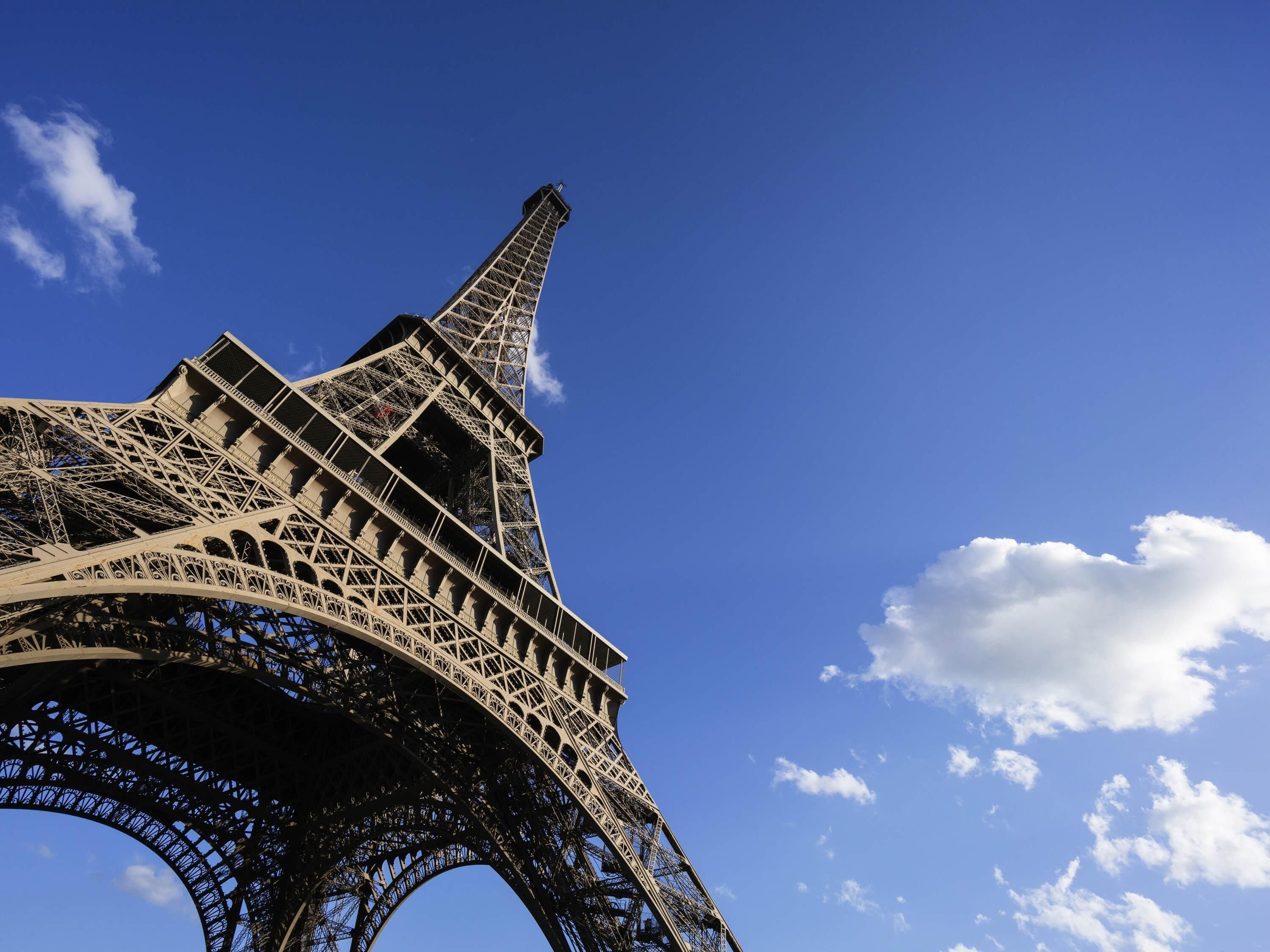 The Eiffel Tower's intricate iron lattice structure against a clear blue sky.