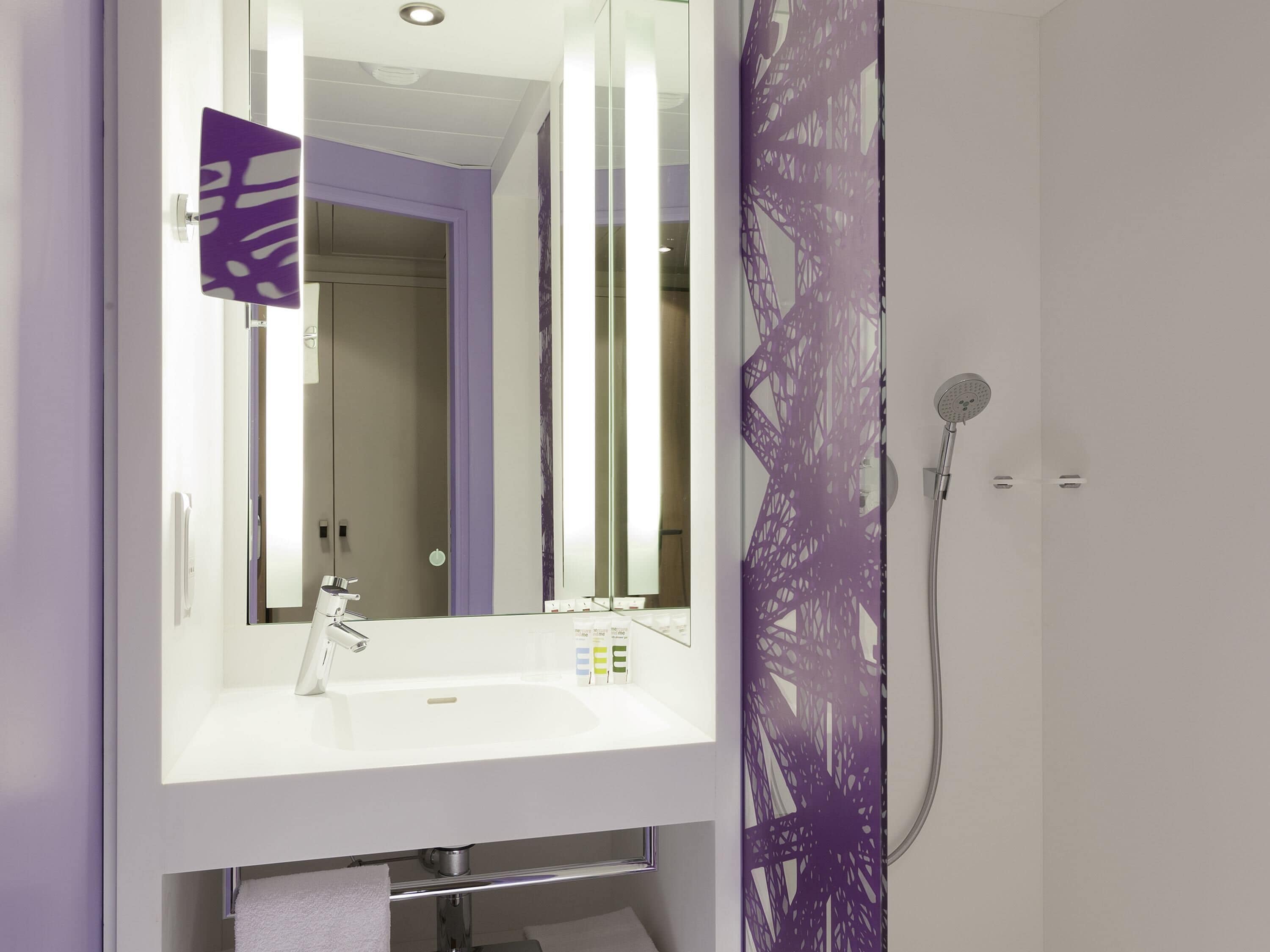 Ein Badezimmer mit einem weißen Waschbecken, einem Spiegel und einer Dusche.