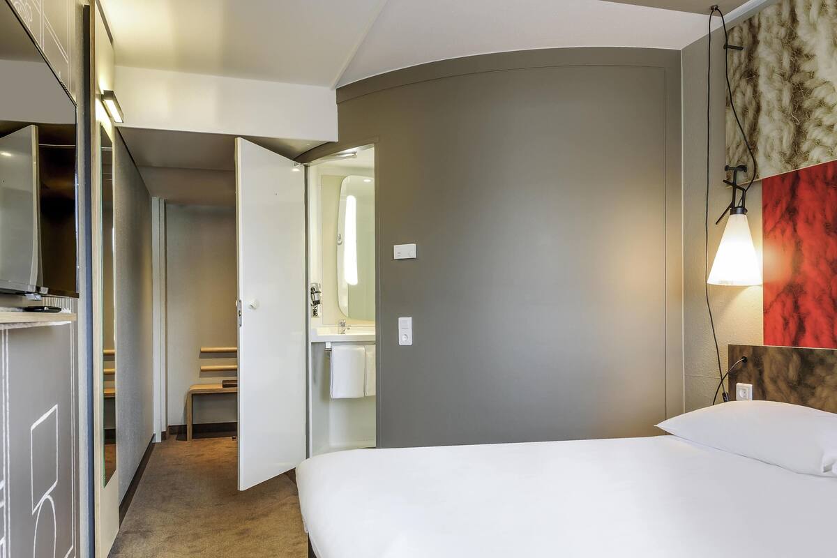 A hotel room with a bed, a bathroom, and a closet.