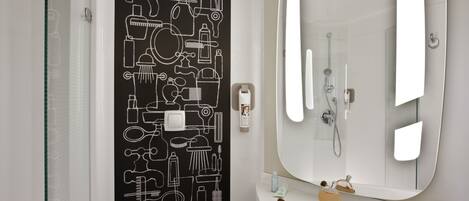 A bathroom with a large mirror, a shower, and a black wall art depicting bathroom items.
