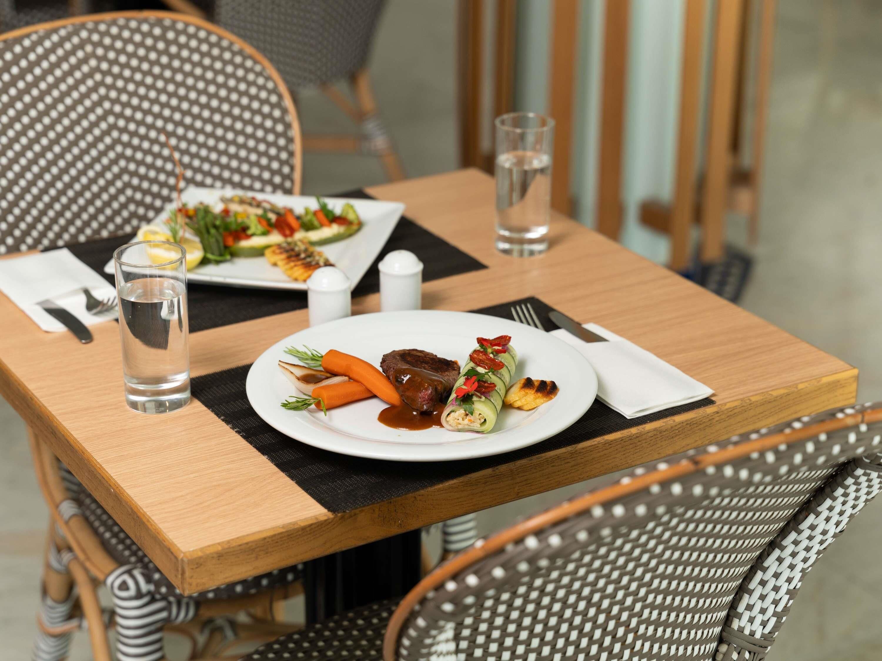 A dining table with a plate of food, a glass of water, and a napkin.