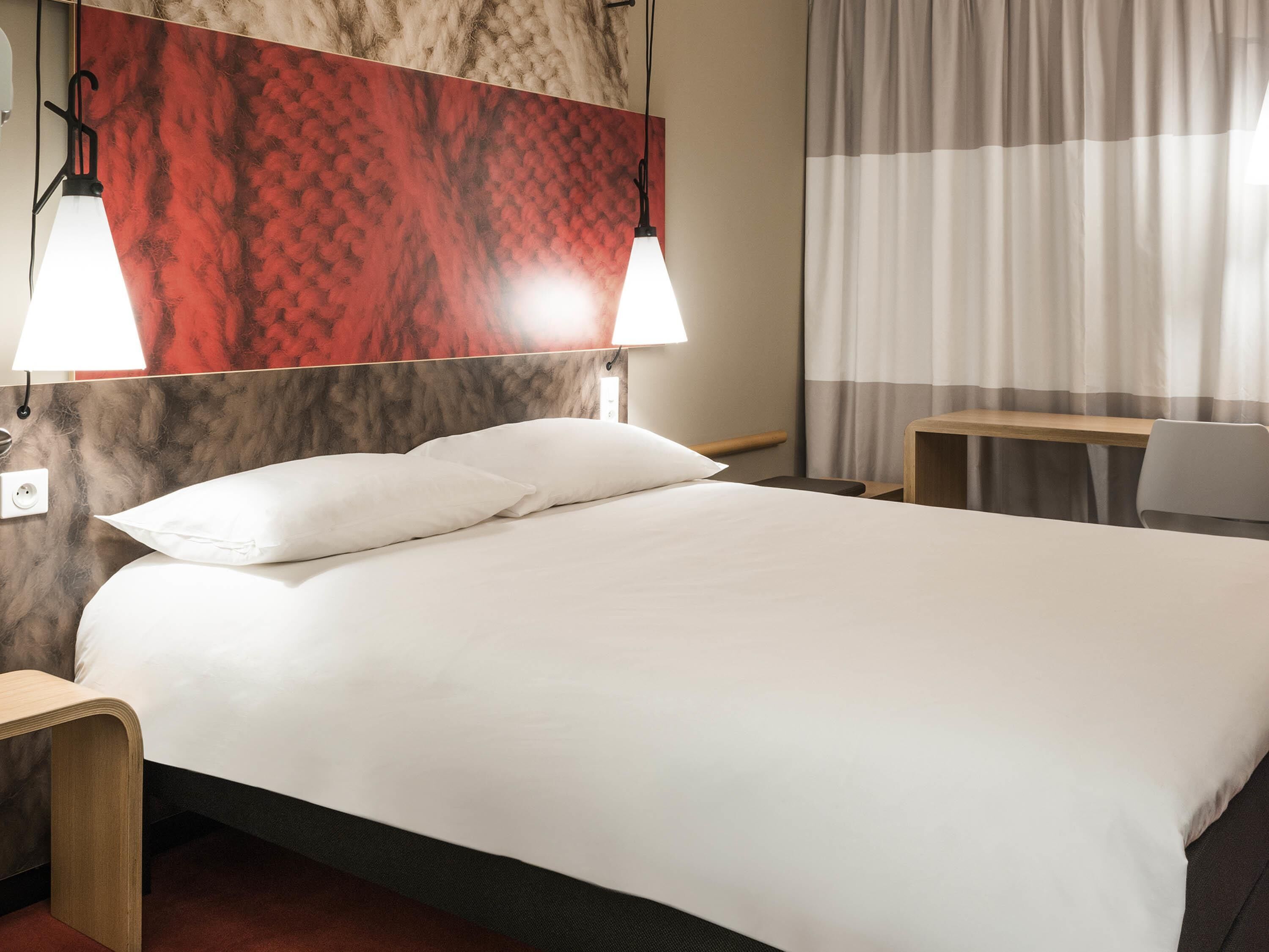 Ein Hotelzimmer mit einem Bett, zwei Nachttischlampen, einem Schreibtisch und einem Stuhl.