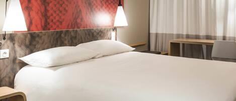 A hotel room with a bed, two bedside lamps, a desk, and a chair.