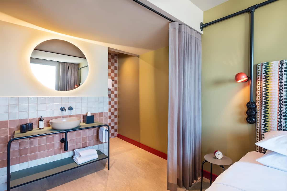 A modern bathroom with a round mirror, a sink, and a towel rack.
