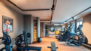 A gym with exercise equipment, a bench, and a poster on the wall. - Me and All Hotel Berlin East Side, by Hyatt - NEW OPENING (Berlin)