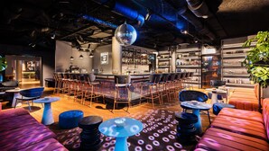 A bar area with a bar counter, seating, and a disco ball. - Me and All Hotel Berlin East Side, by Hyatt - NEW OPENING (Berlin)