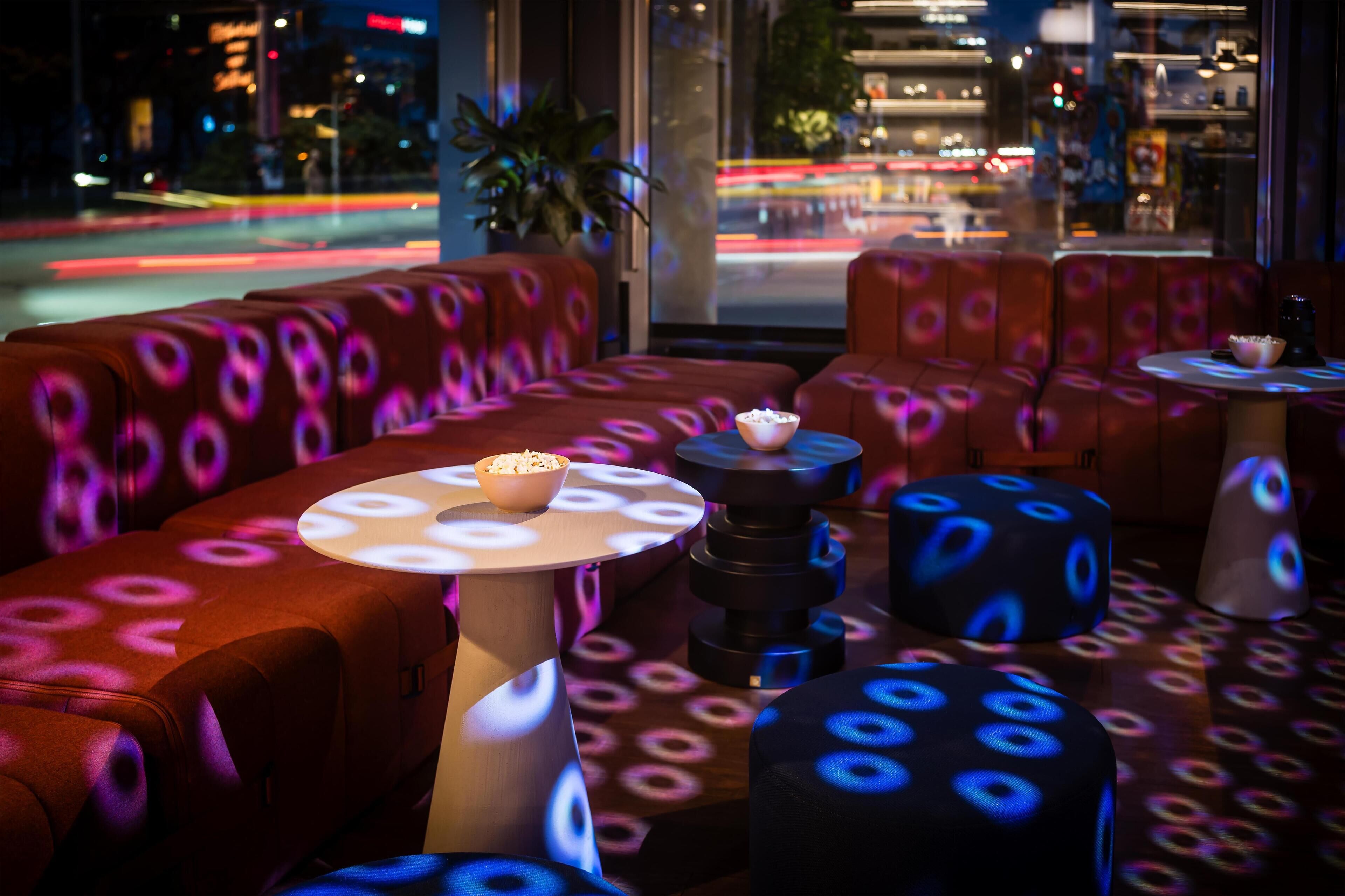 A modern lounge with circular patterned seating and a bowl of popcorn on a table.