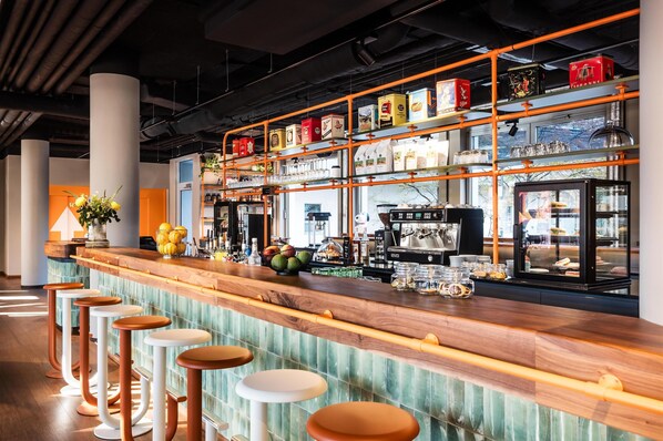 A bar area with stools, shelves of beverages, and a coffee machine. - Me and All Hotel Berlin East Side, by Hyatt - NEW OPENING (Berlin)
