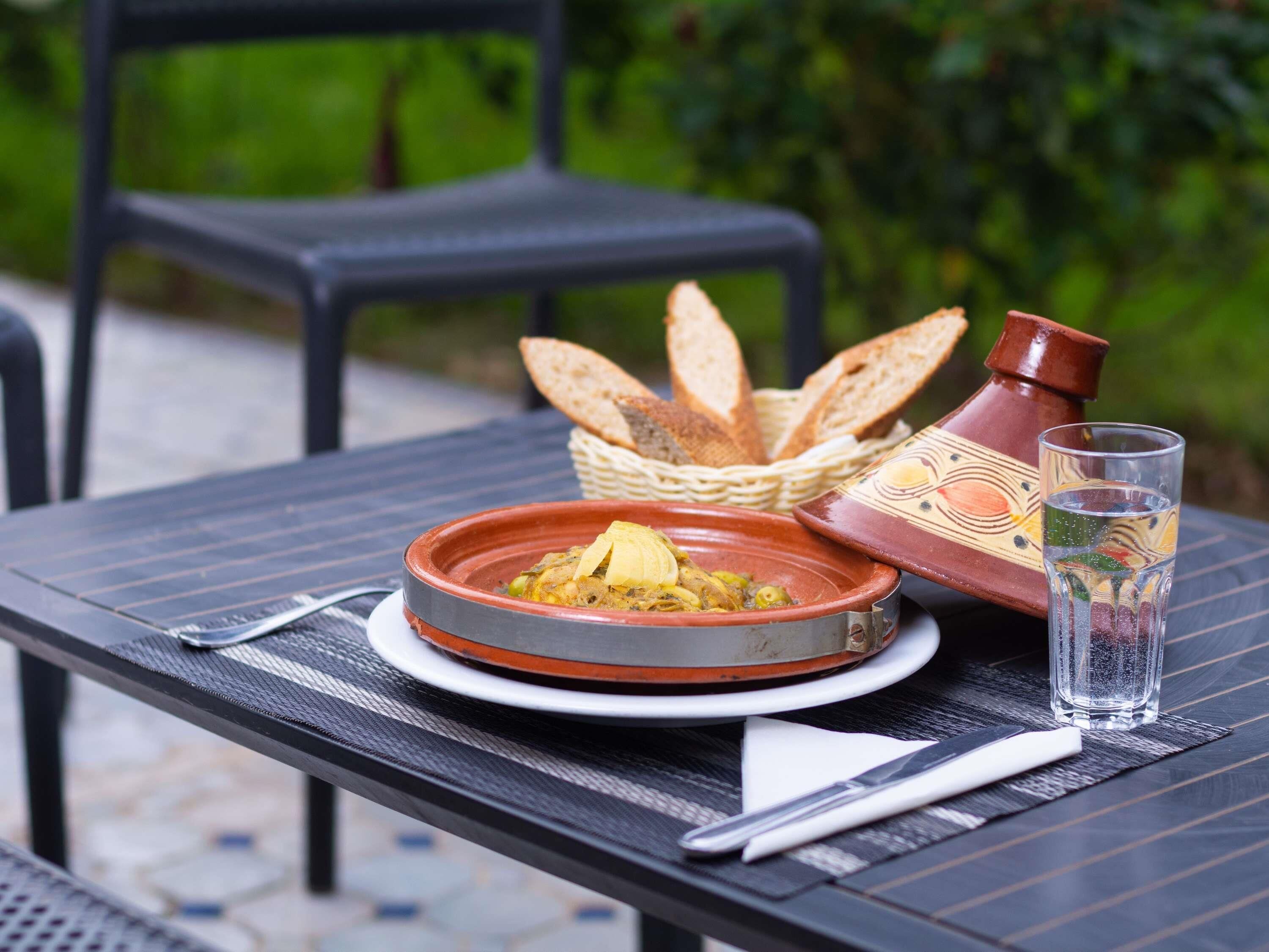 A dining table with a bowl of food, a glass of water, a bread basket, and a decorative pot.