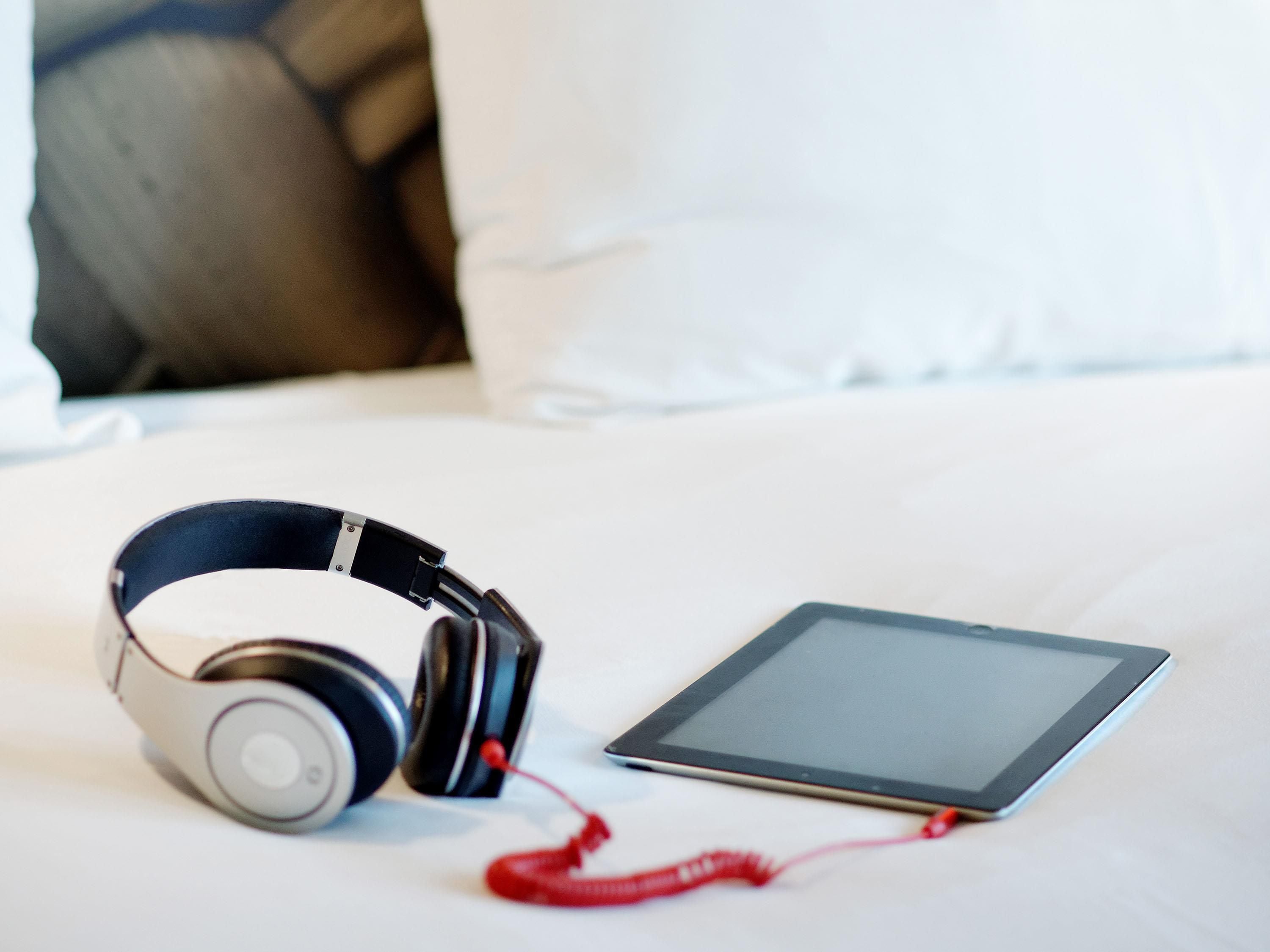 A bed with a tablet and headphones on it.