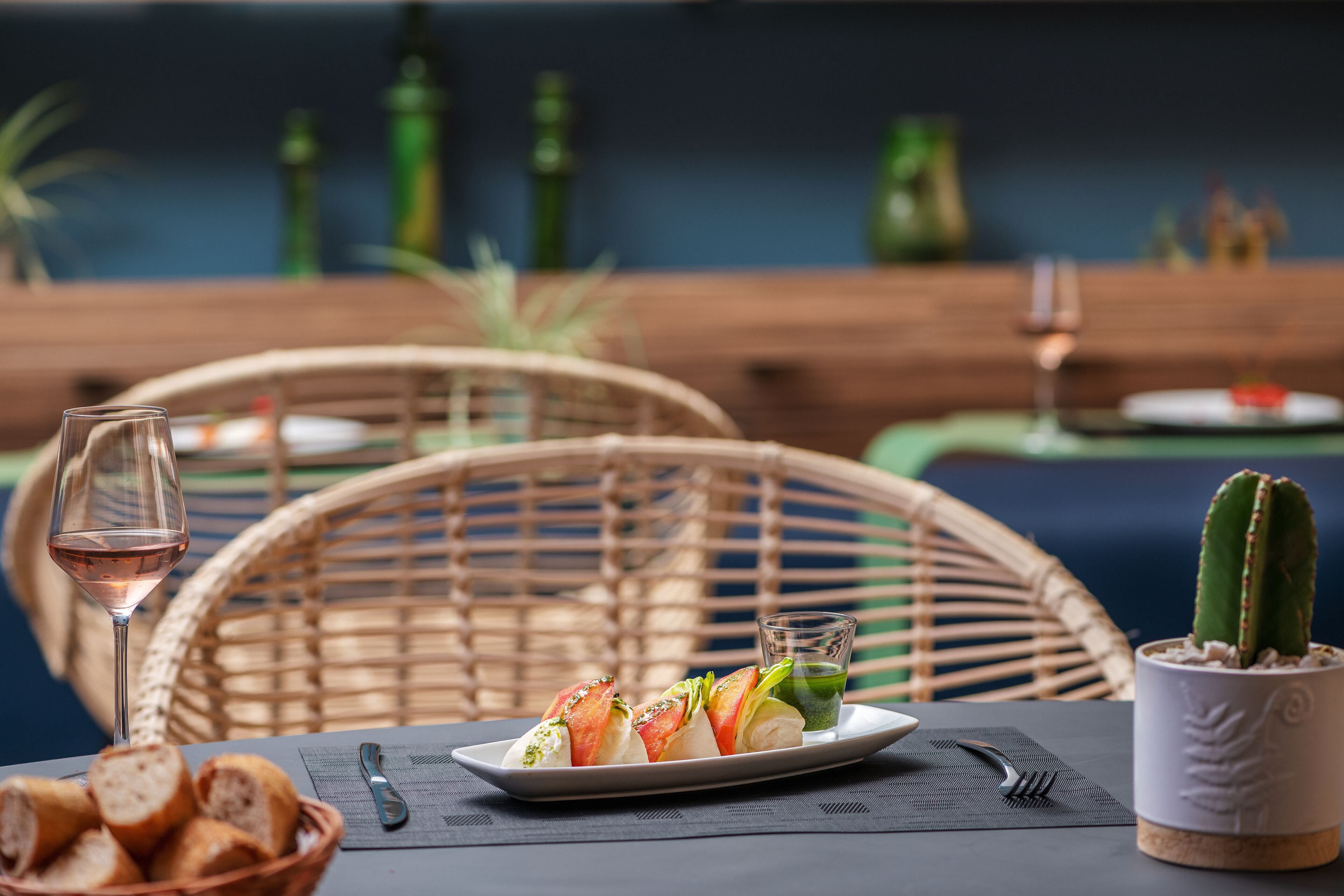 Una mesa de comedor con un plato de comida, una copa de vino y una maceta con un cactus.