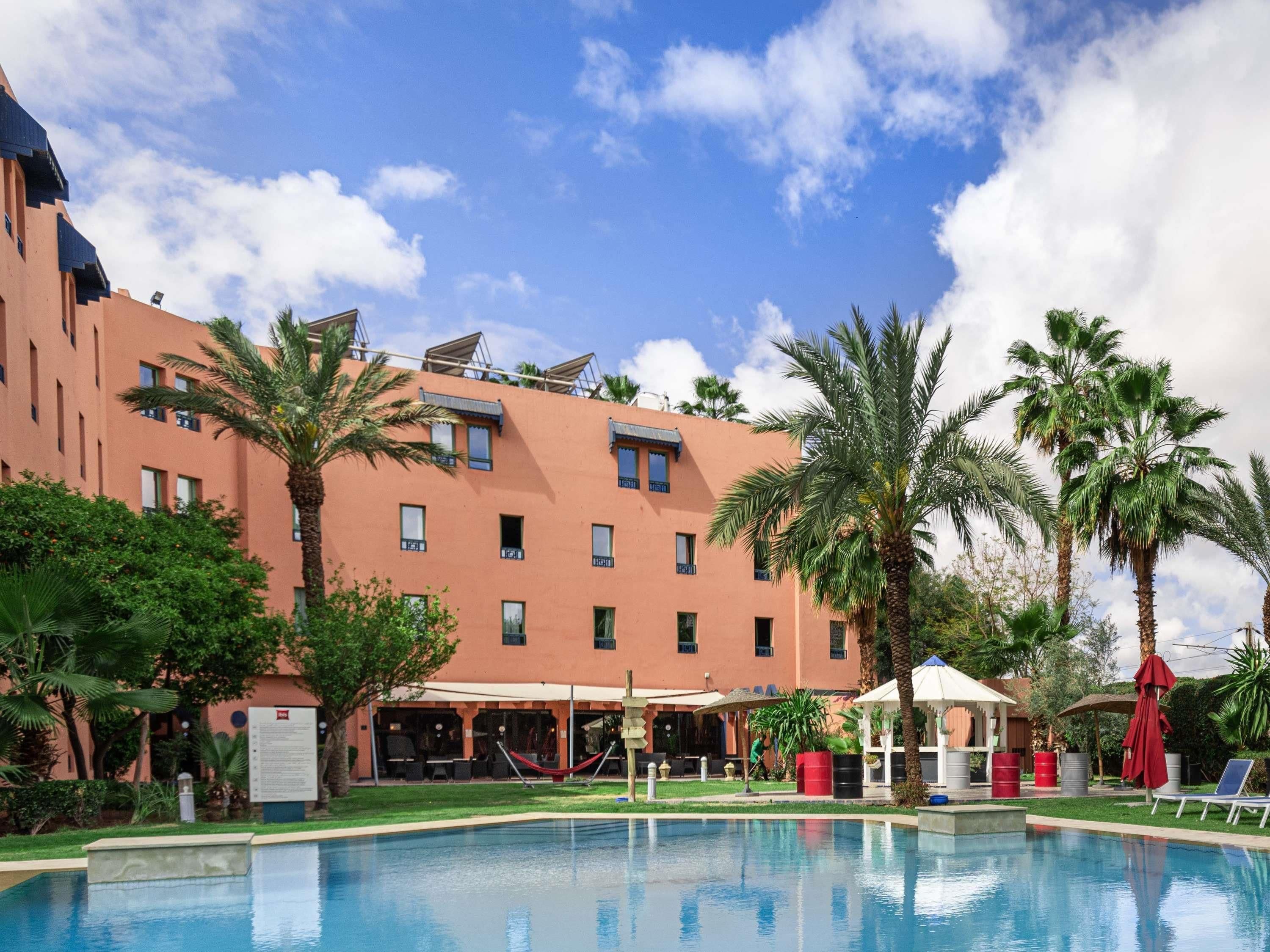 Un hotel con piscina, palmeras y cielo despejado.