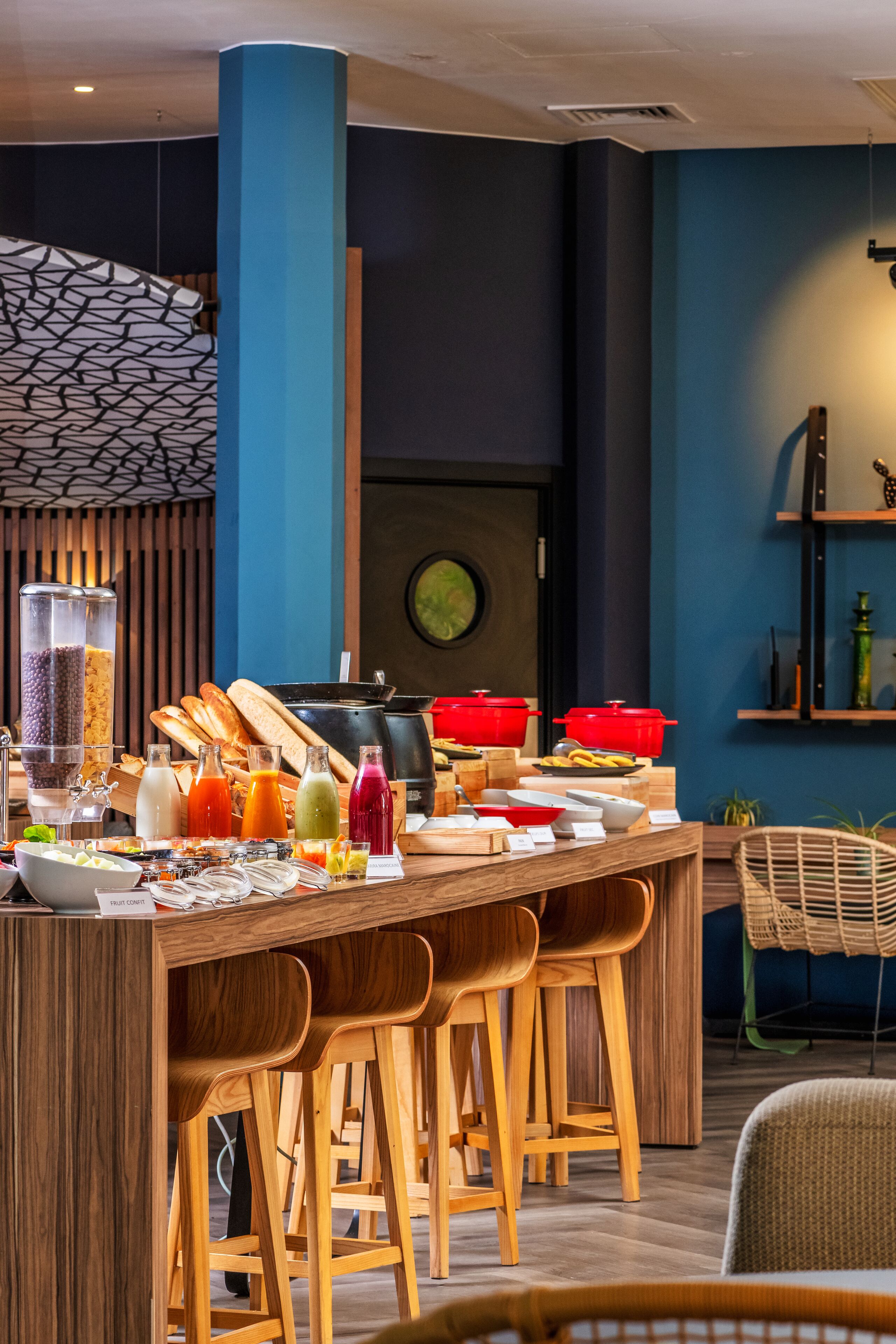 Un comedor moderno con una barra de madera, taburetes y una variedad de comida y bebidas.