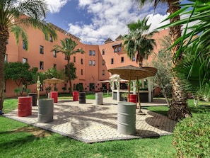 A courtyard with palm trees, outdoor seating, and a building with multiple windows.