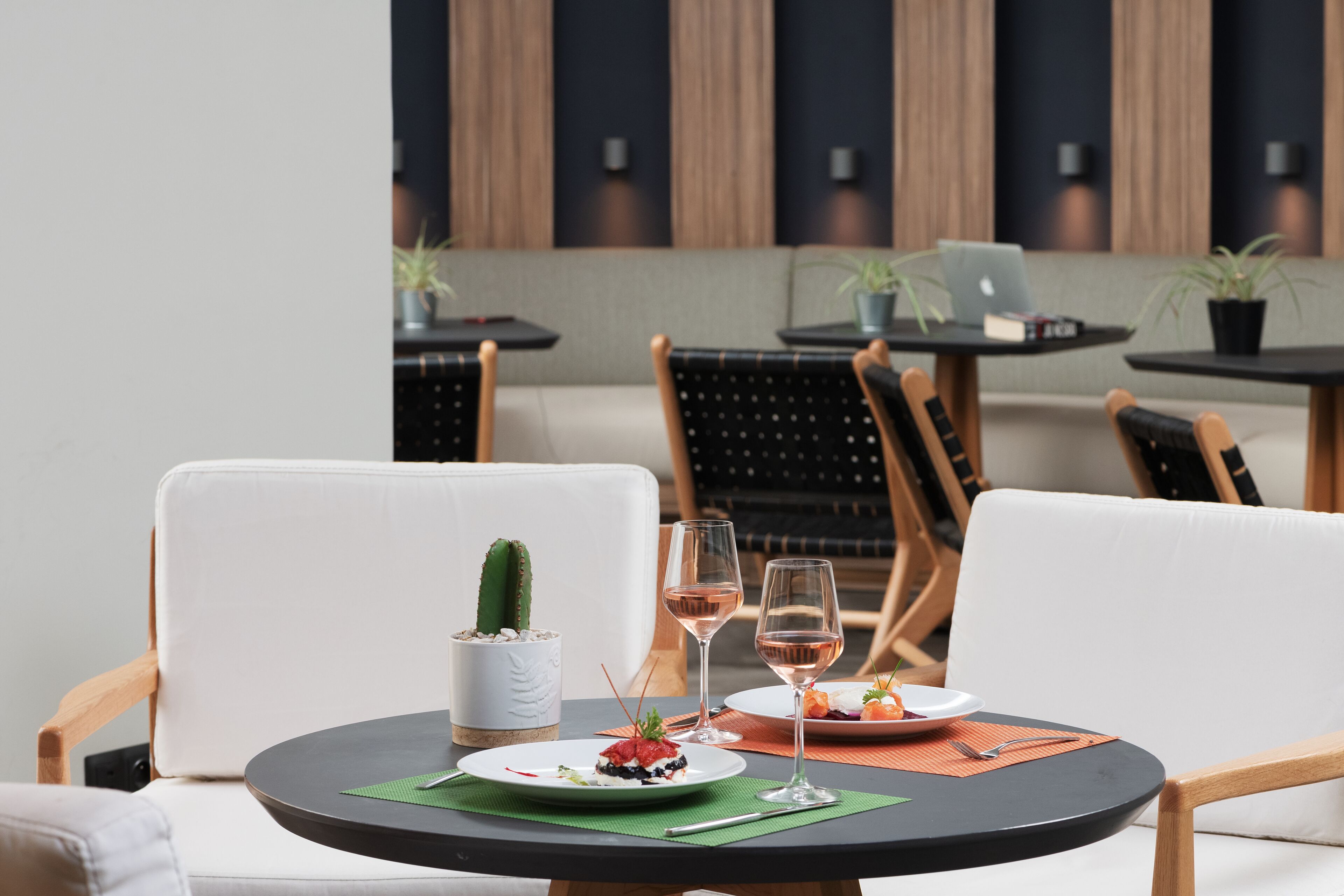 A dining area with round tables, white cushioned chairs, and a cactus centerpiece.