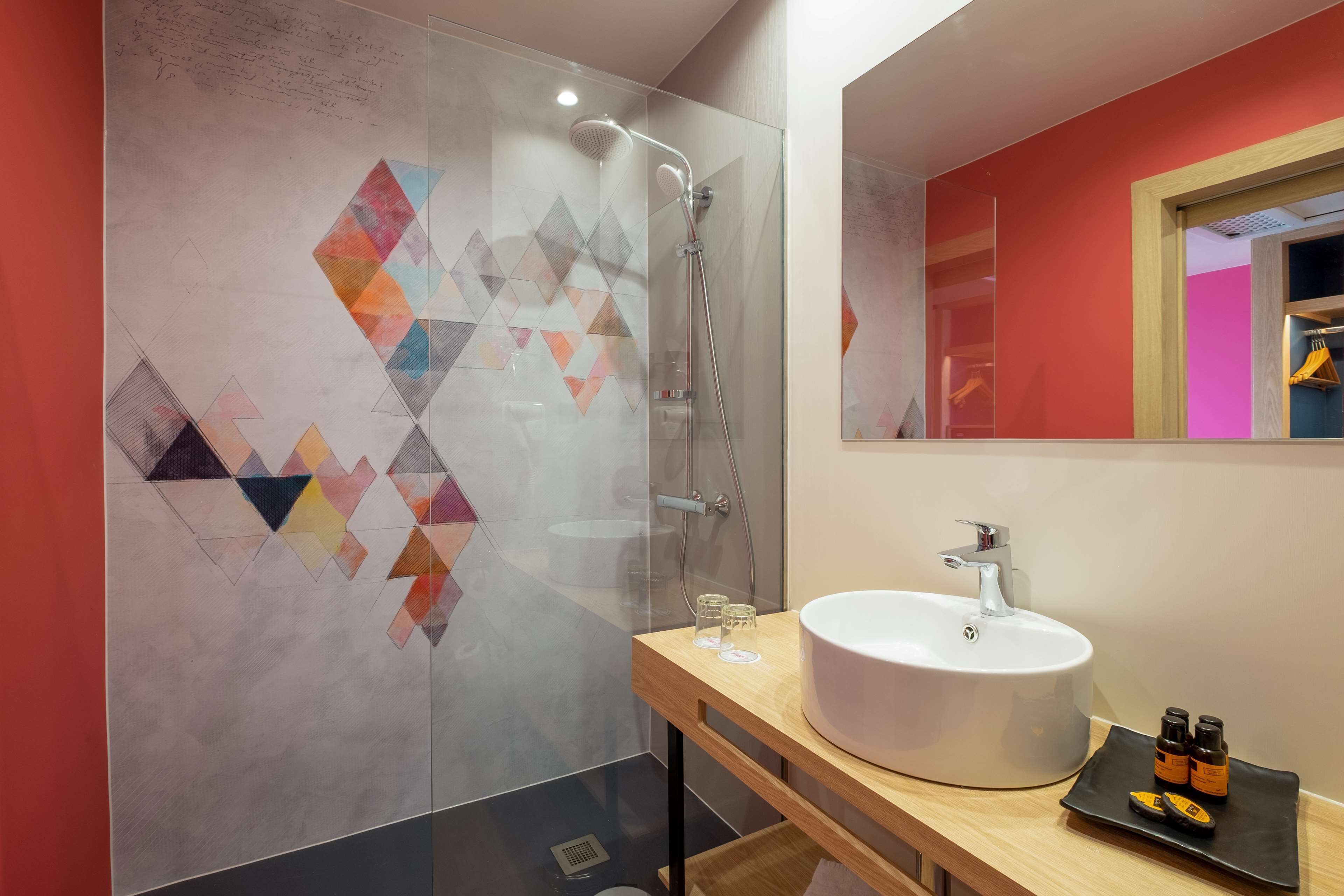 Ein modernes Badezimmer mit Duschkabine aus Glas, einem weißen Waschbecken und einem Spiegel darüber.