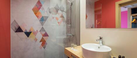 Un baño moderno con cabina de ducha de vidrio, un lavabo blanco y un espejo sobre él.