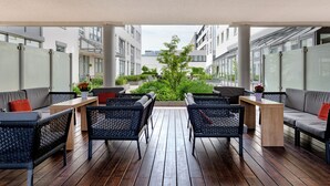 An outdoor patio with wooden flooring, wicker furniture, and potted plants. - Mercure Hotel Stuttgart Airport Messe (Stuttgart)