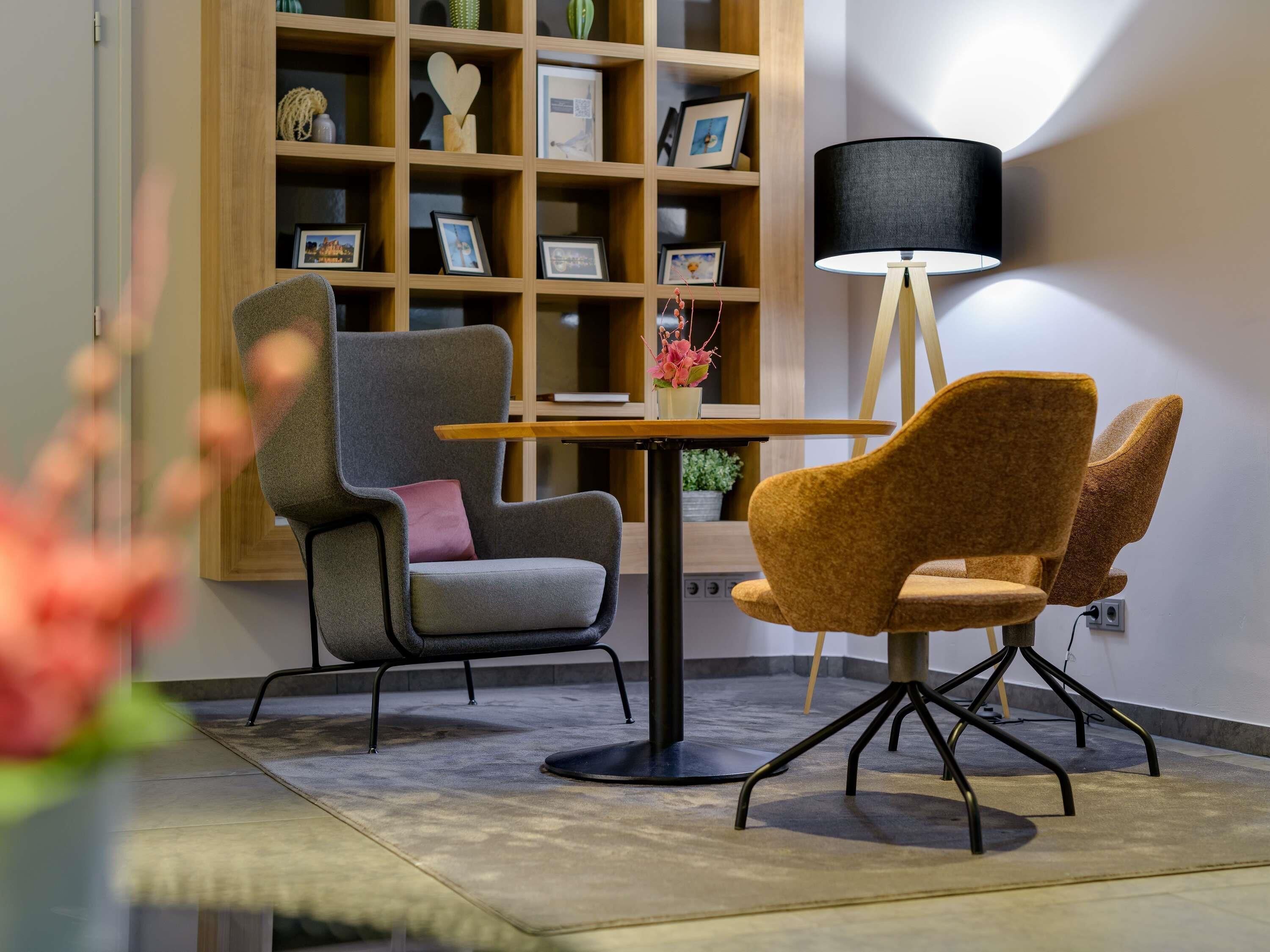 Une pièce moderne avec une bibliothèque en bois, une table ronde et deux chaises.