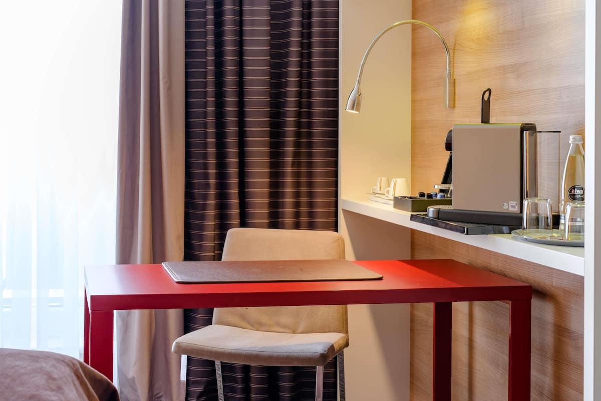 A hotel room with a desk, chair, and a minibar.