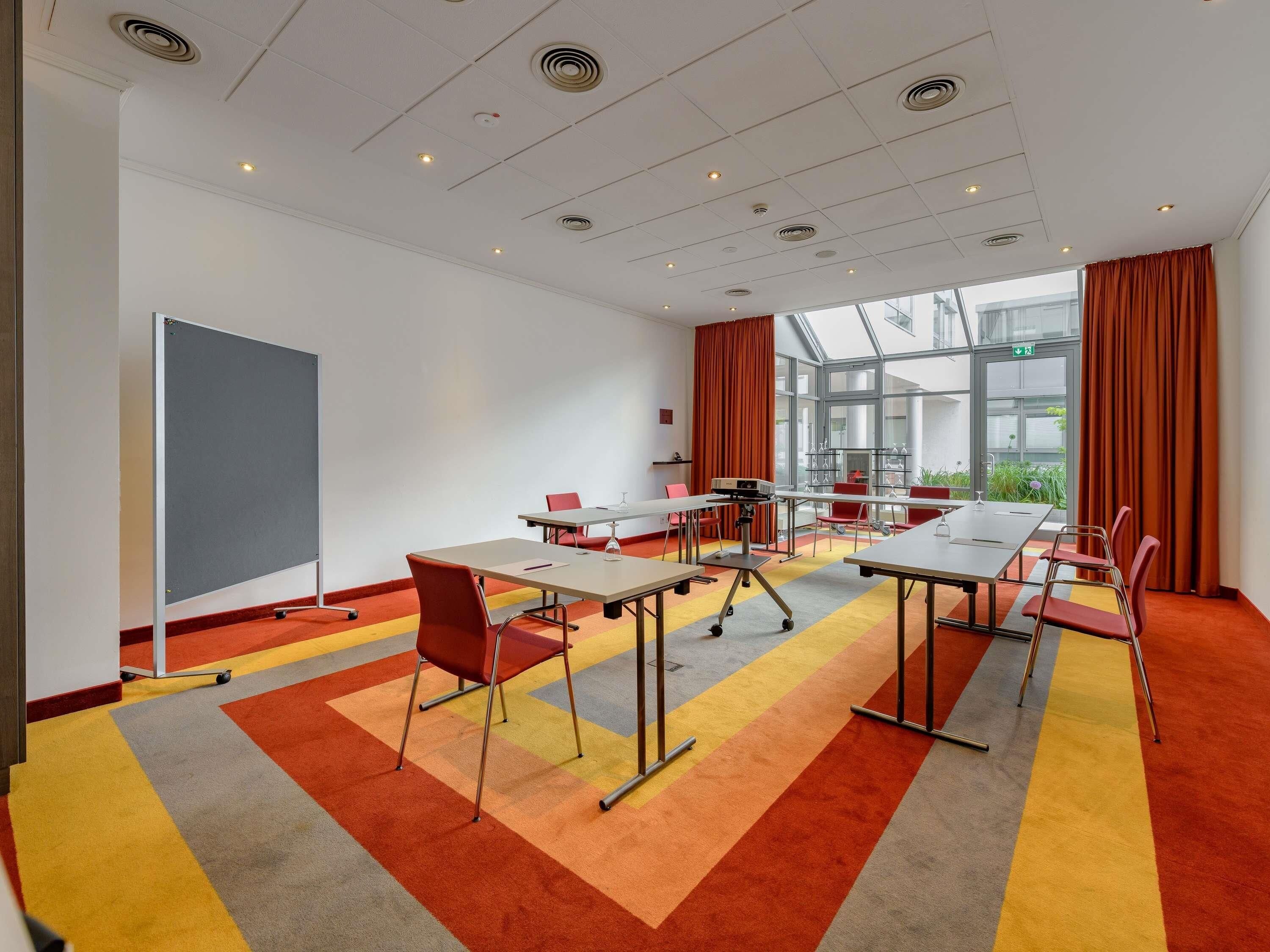 Una sala de conferencias moderna con una gran mesa, sillas, un proyector y vistas amplias a través de grandes ventanales.