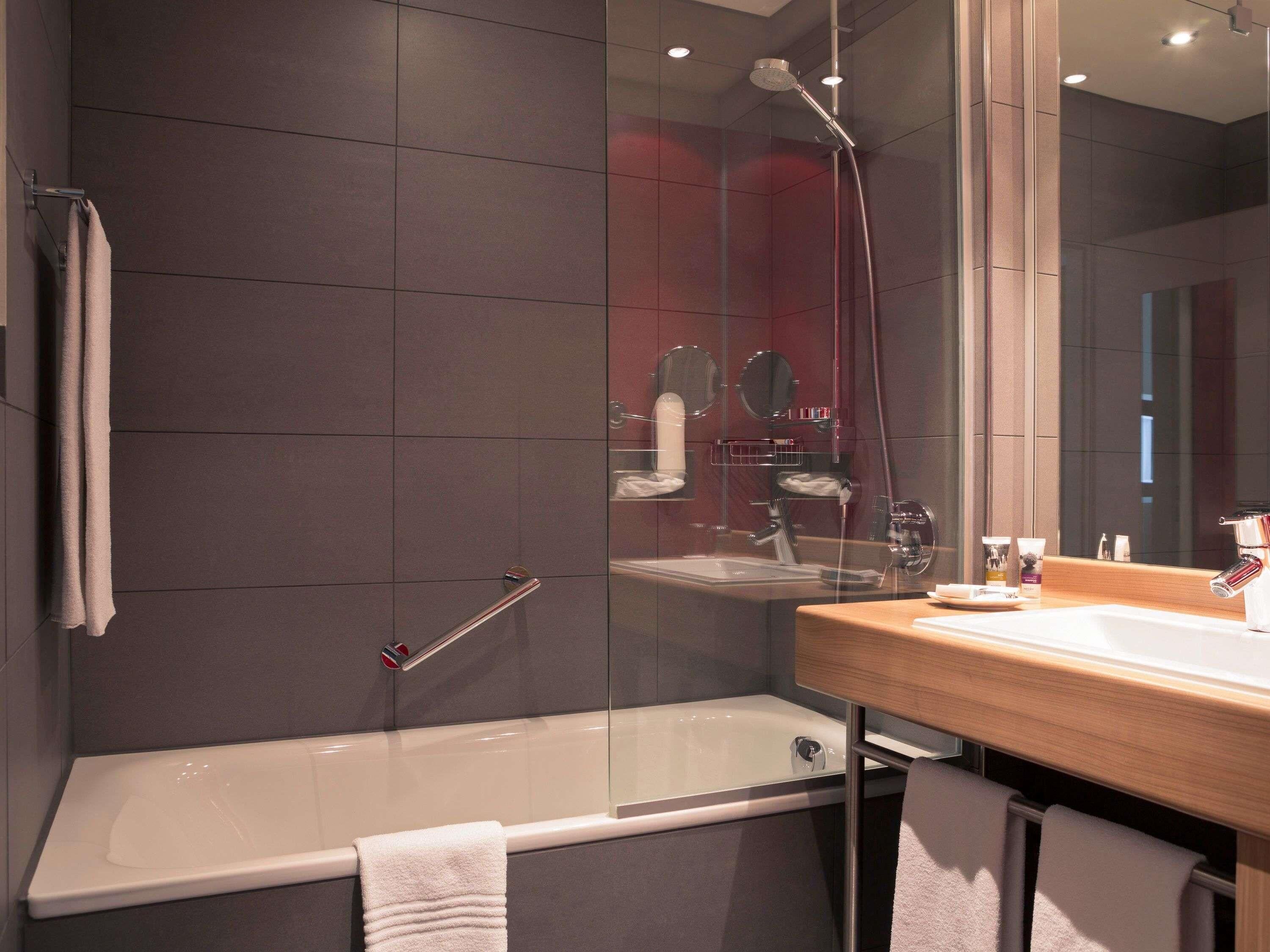 Ein modernes Badezimmer mit Duschkabine aus Glas, einer Badewanne und einem Holzbadezimmer-Möbelstück inklusive Spiegel.