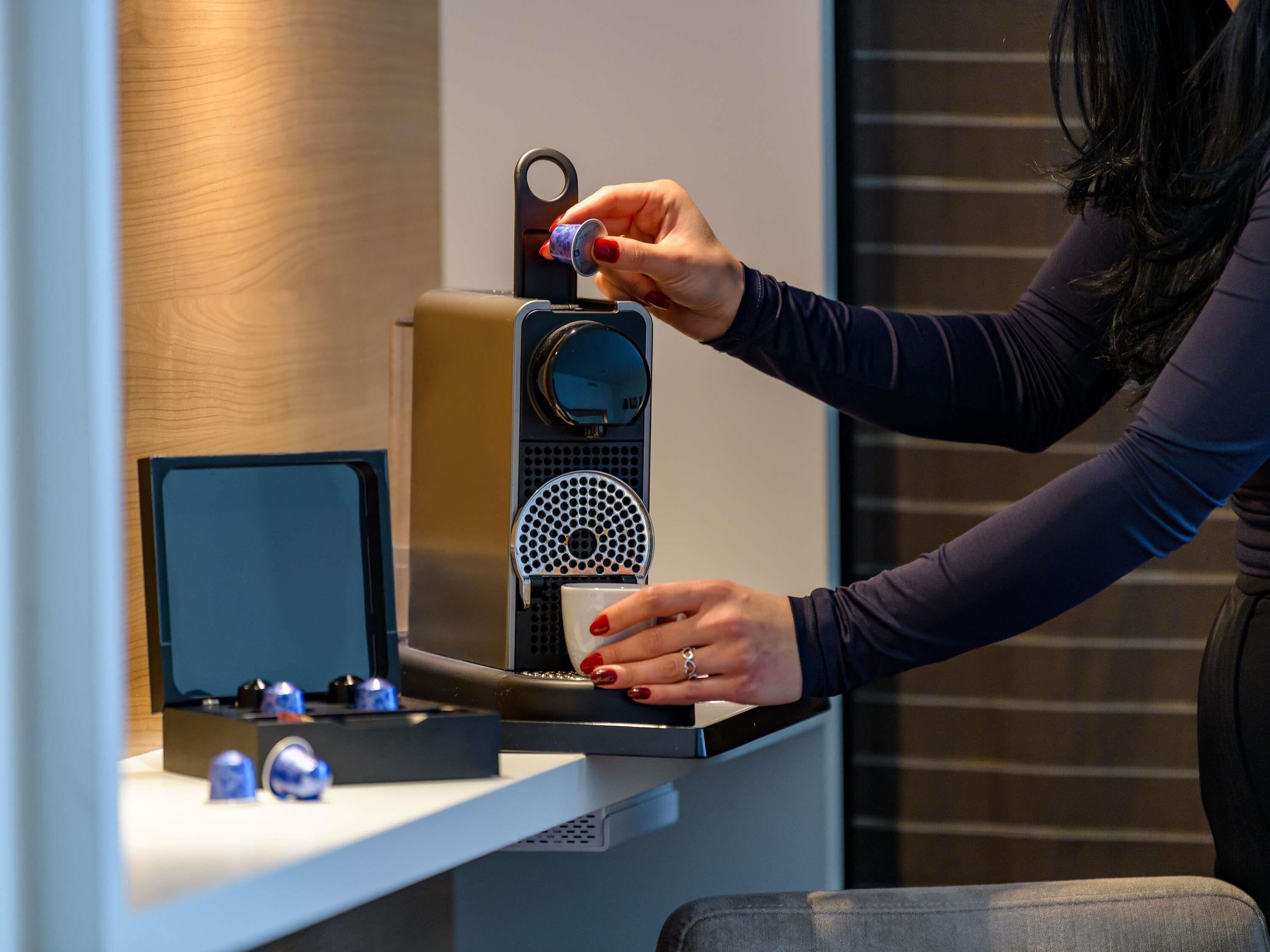 Une personne utilisant une machine à café dans une cuisine moderne.