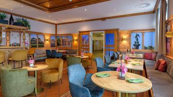 Un restaurante con techo de madera, varias zonas de estar y ventanas amplias.