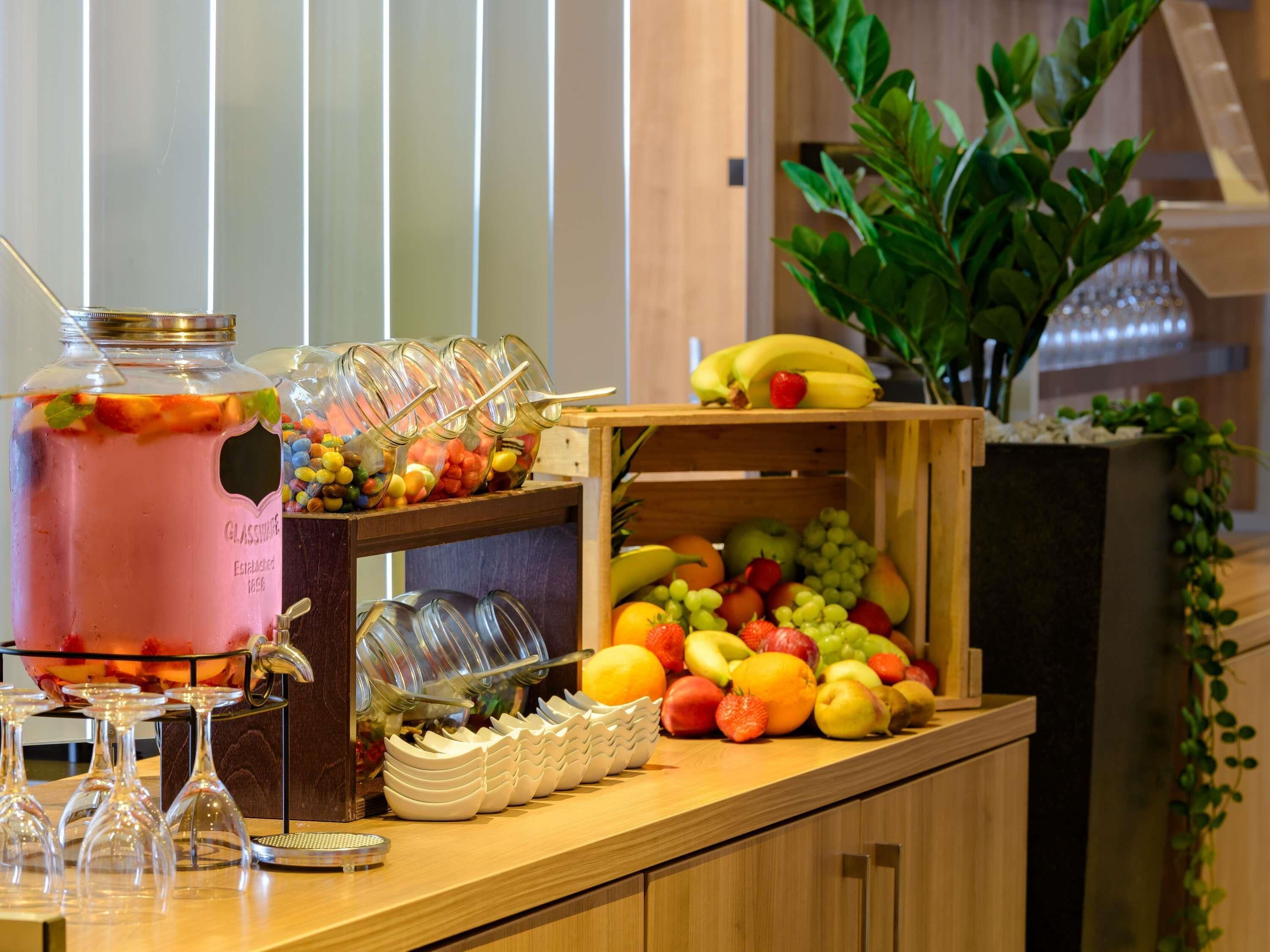 Un buffet comprenant un distributeur de punch aux fruits, une variété de fruits et un présentoir à verres.