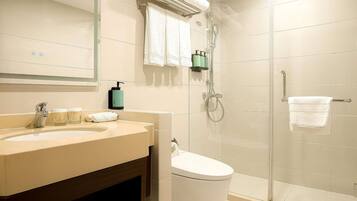 A bathroom with a sink, mirror, towel rack, shower, and toilet.