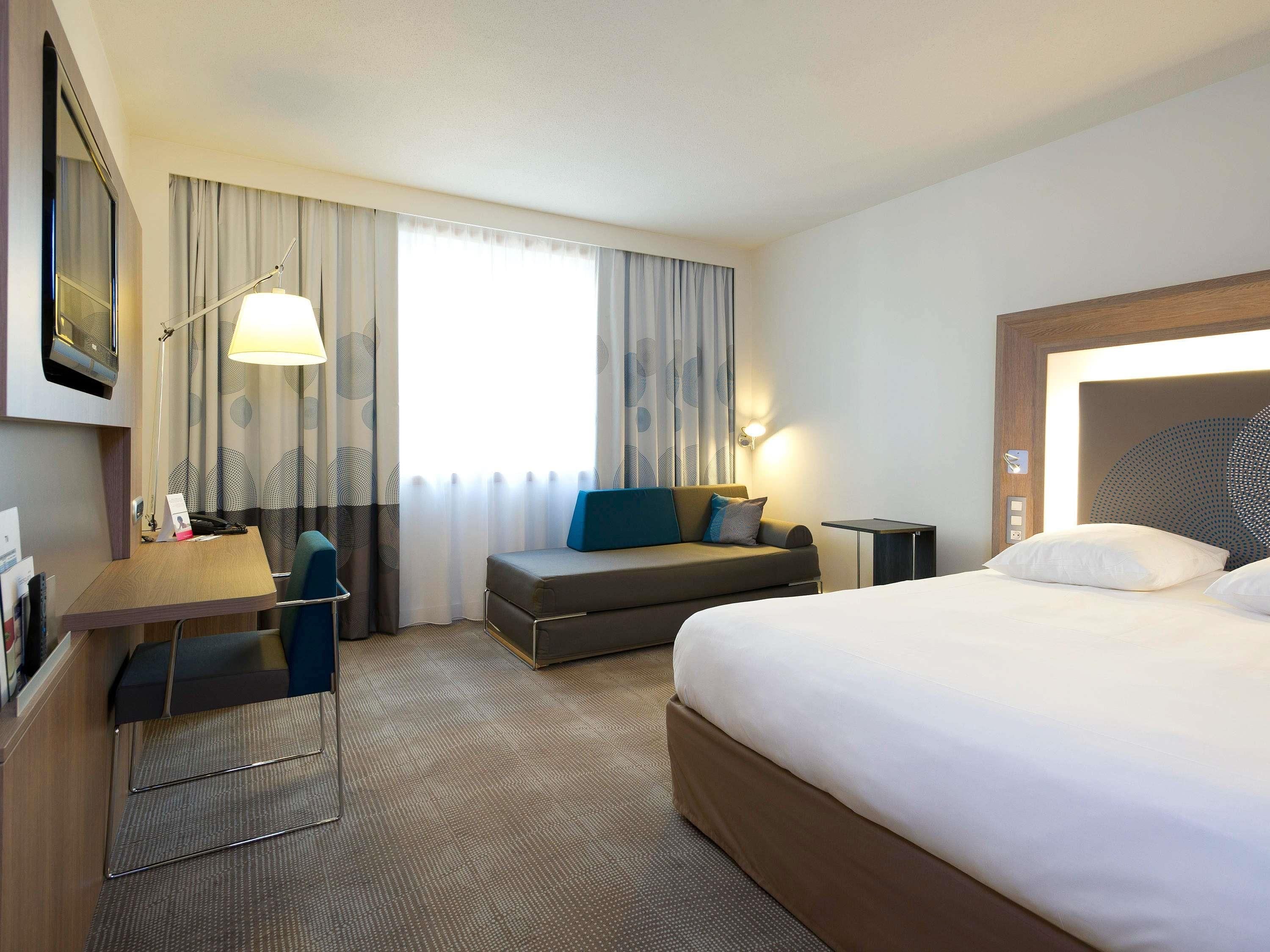 Une chambre d’hôtel équipée d’un lit, d’un bureau, d’une chaise, d’un canapé, d’une lampe et d’un téléviseur.