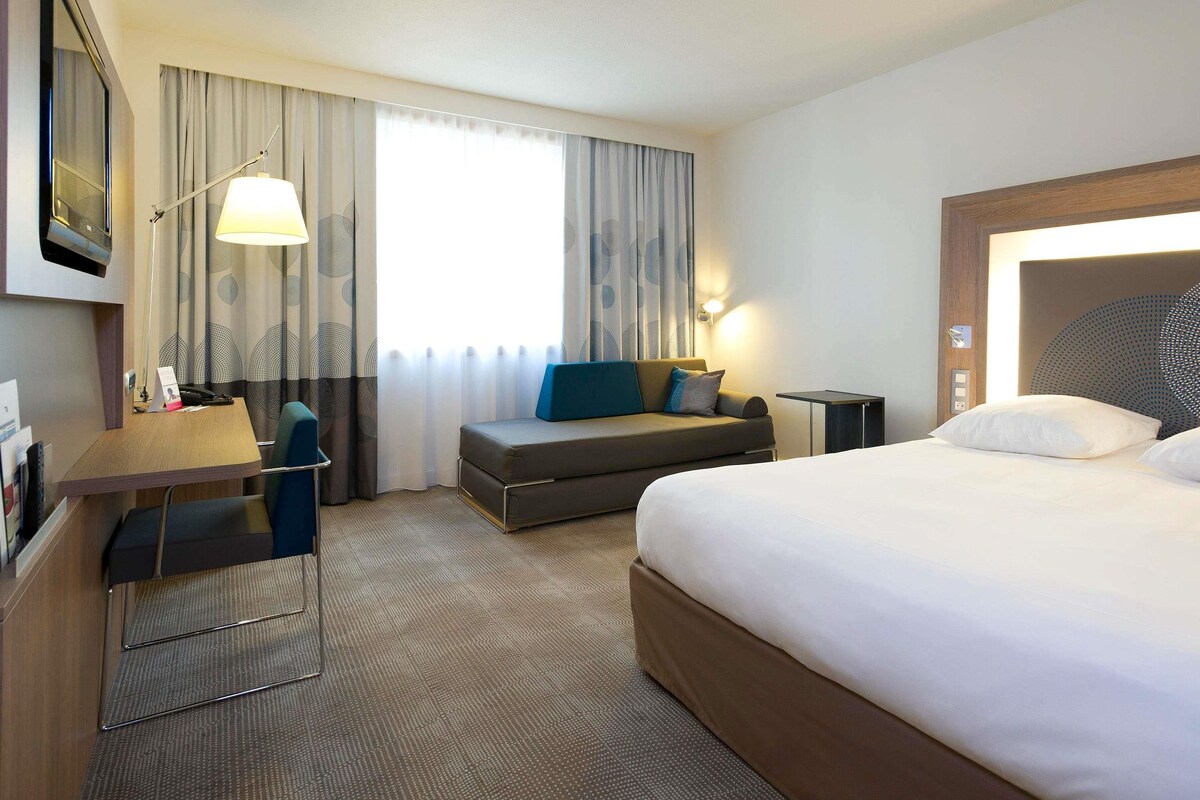 Une chambre d’hôtel équipée d’un lit, d’un bureau, d’une chaise, d’un canapé, d’une lampe et d’un téléviseur.
