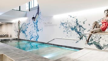 Een binnenzwembad, ligstoelen bij het zwembad