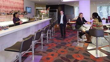Un espace bar moderne avec un long comptoir, des tabourets de bar et un tapis à motifs.