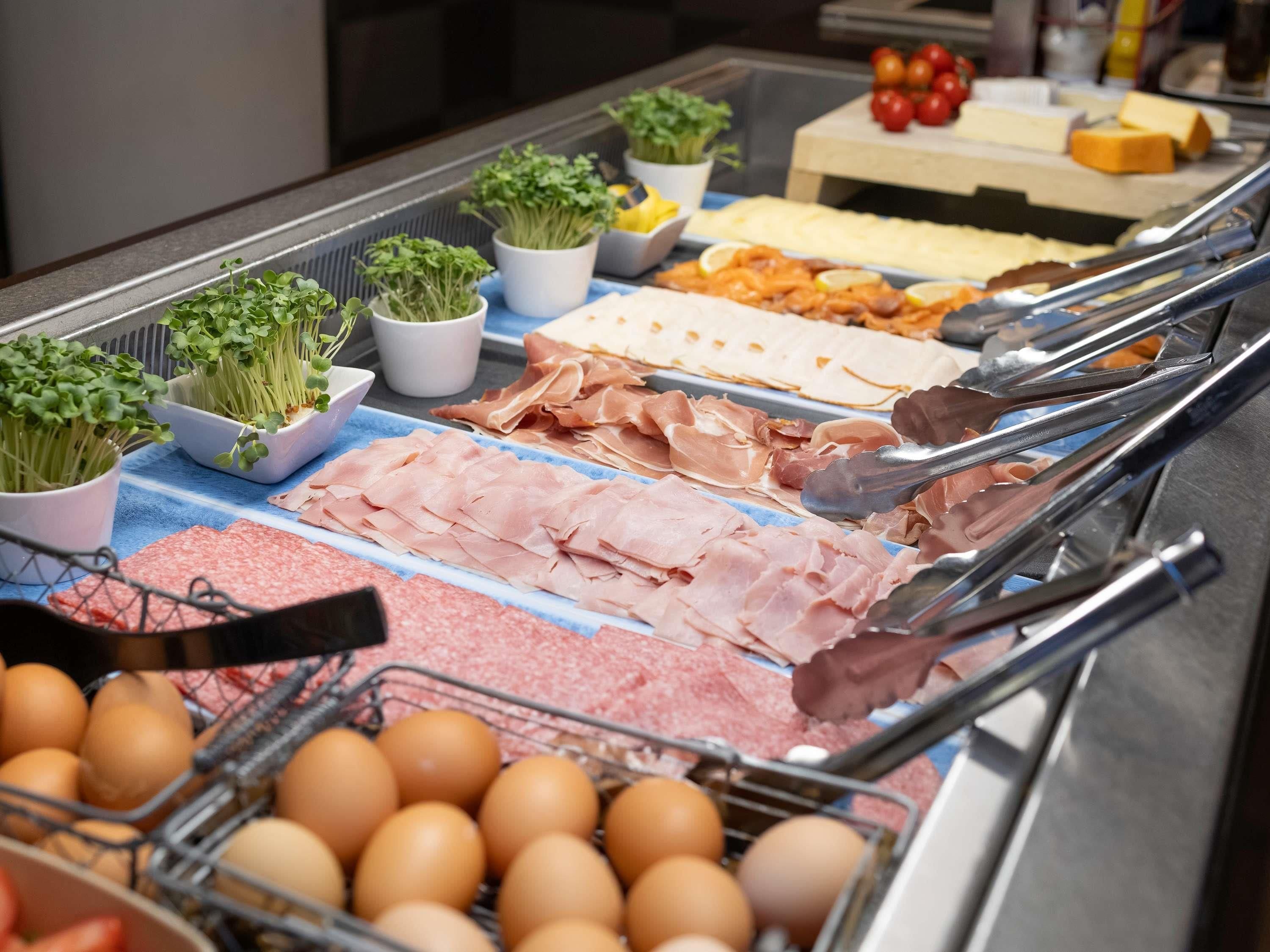 Ein reichhaltiges Buffet mit verschiedenen Speisen, darunter Fleisch, Käse und Eier.
