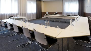 Une salle de conférence avec une longue table, des chaises et des bouteilles d’eau.