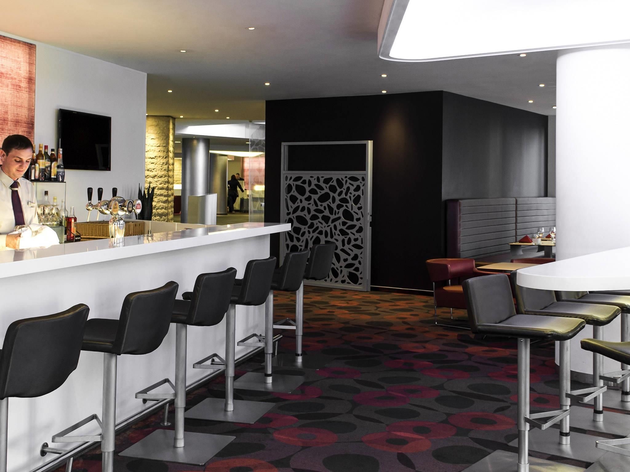 A modern bar area with a counter, bar stools, and a patterned carpet.
