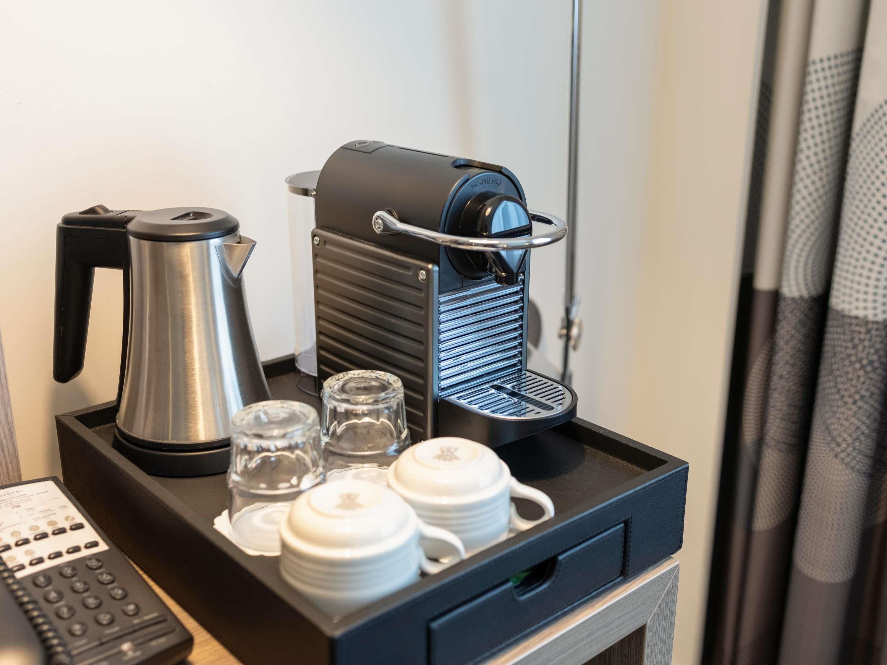 A coffee machine on a tray with a kettle, glasses, and teapots.