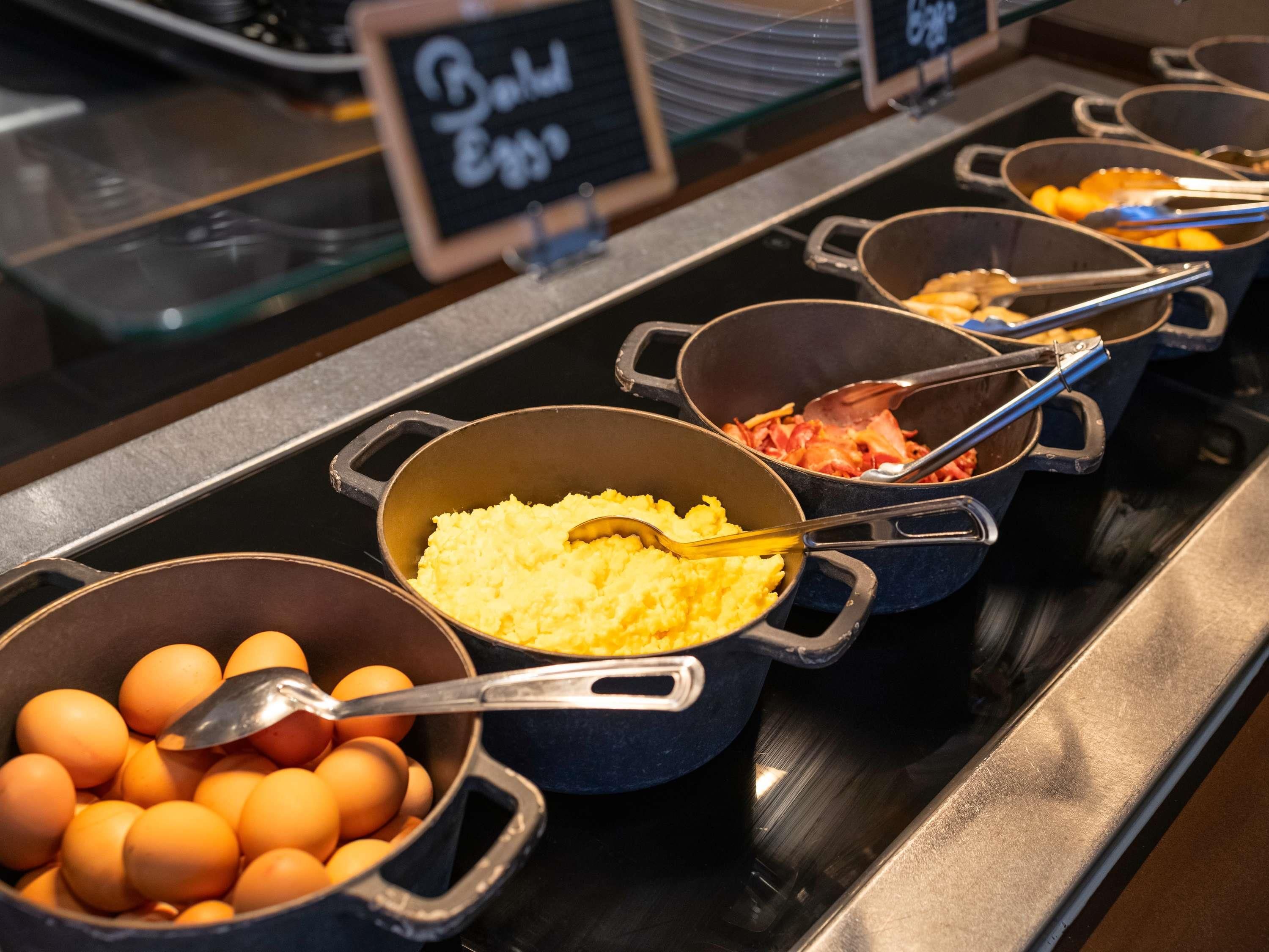 Un bufé con diversos alimentos, entre ellos huevos, patatas y carne.