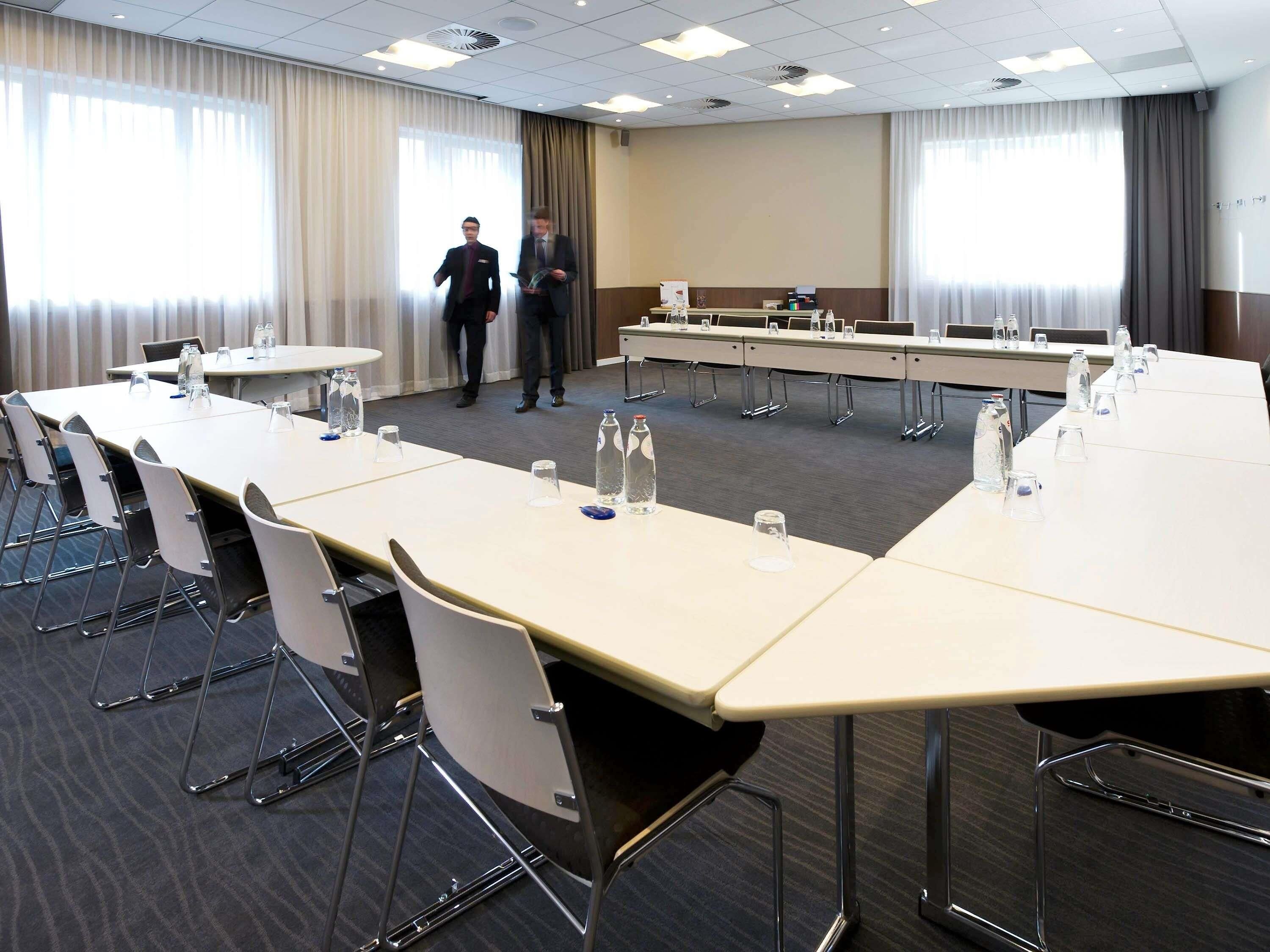 A conference room with long tables, chairs, and water bottles.