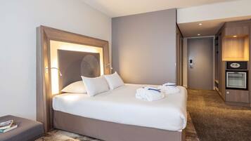 Habitación de hotel con cama, escritorio, calefactor de pared y minibar.