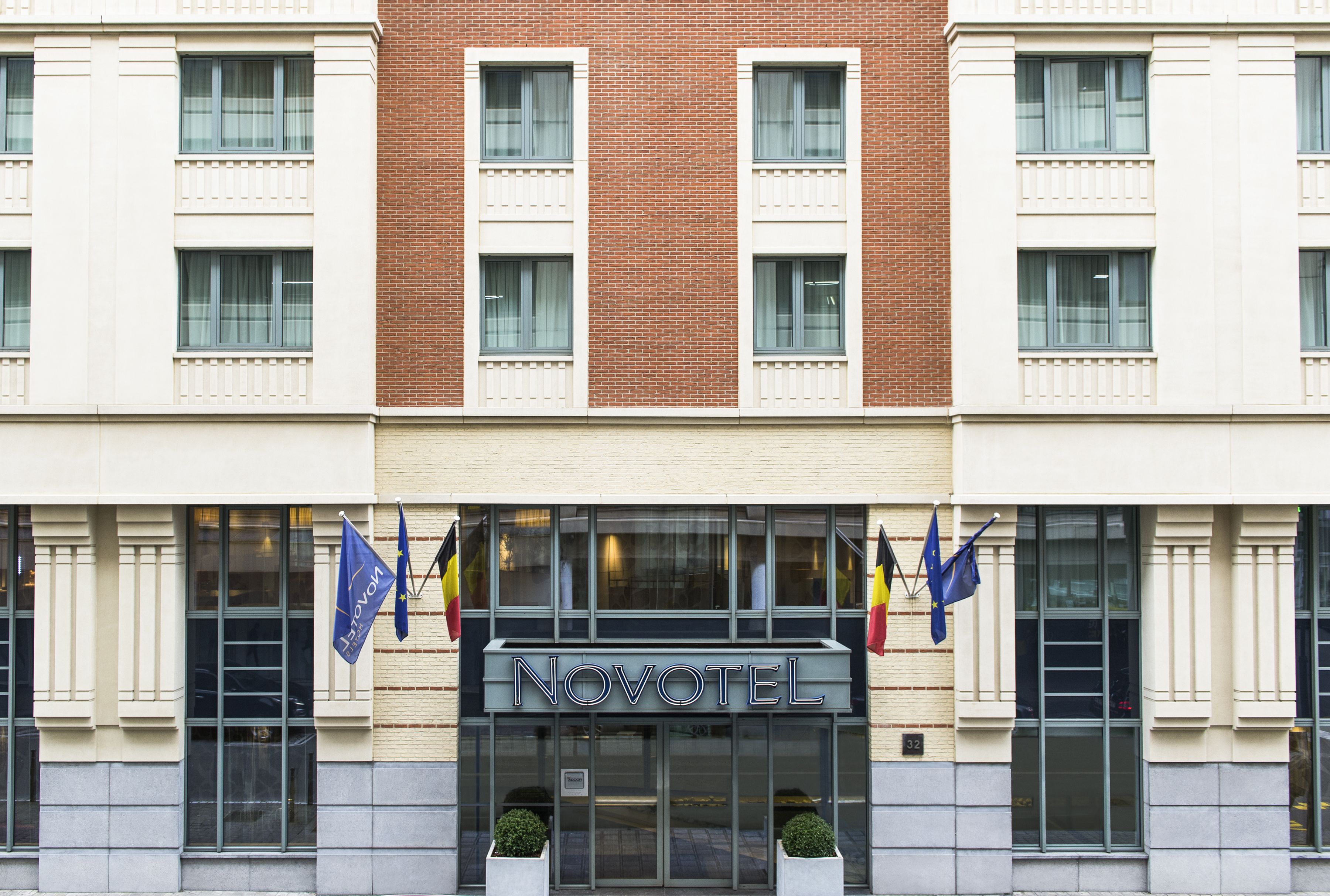 A hotel with a brick facade, multiple windows, and flags.