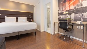 A modern hotel room with a large bed, a desk with a chair, and a cityscape mural on the wall. - Mercure Sao Paulo Vila Olimpia (São Paulo)