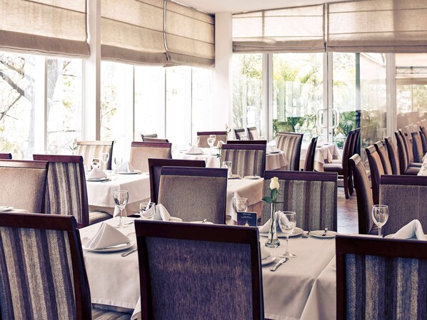 Enjoy a serene dining experience with beautifully set tables, crisp linens, and a vase of fresh flowers.