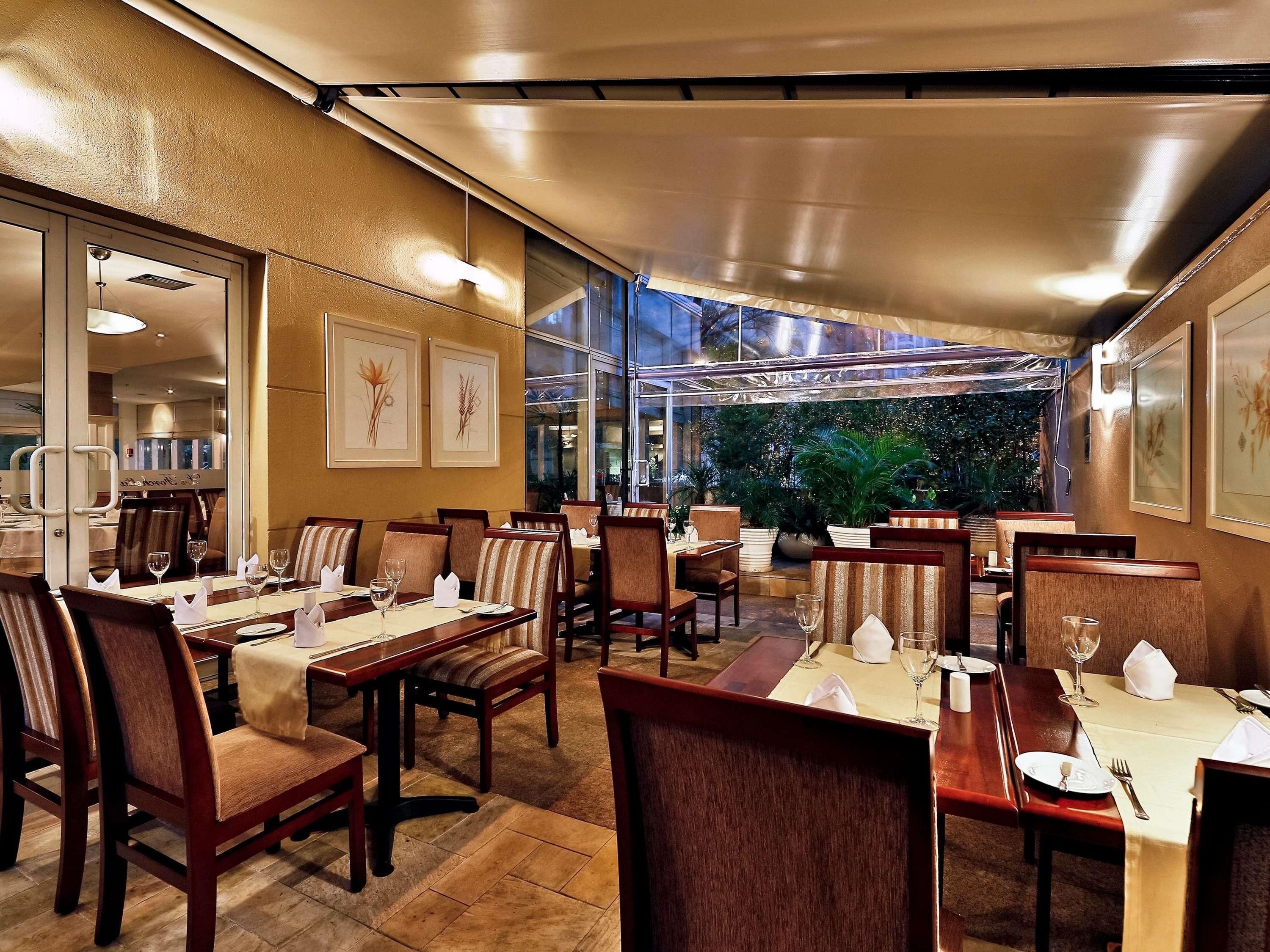 A restaurant with indoor seating, tables set with white tablecloths, and framed artwork on the walls.