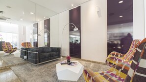 A modern lobby with a black sofa, colorful armchairs, a white coffee table, and a large mirror. - Mercure Sao Paulo Vila Olimpia (São Paulo)